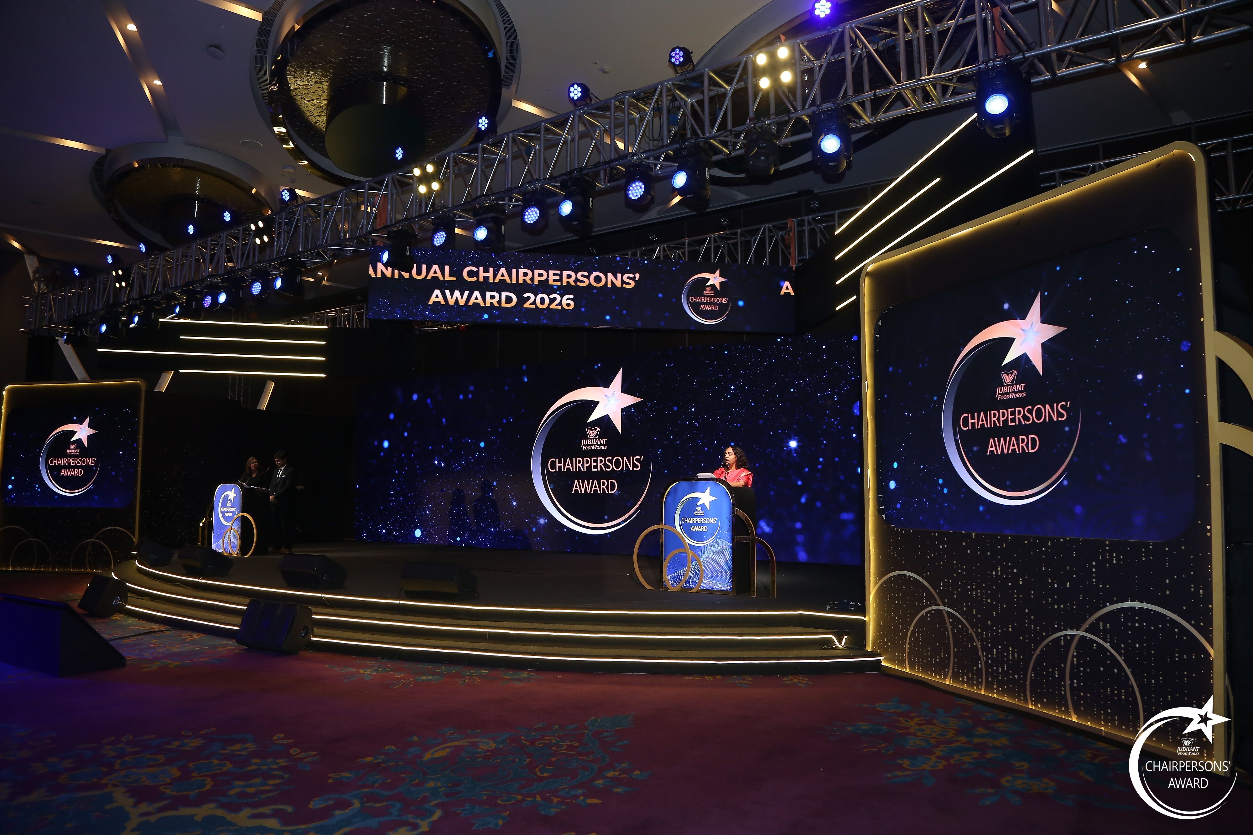 Host addressing the room from the branded podium at the Jubilant FoodWorks Chairpersons' Award